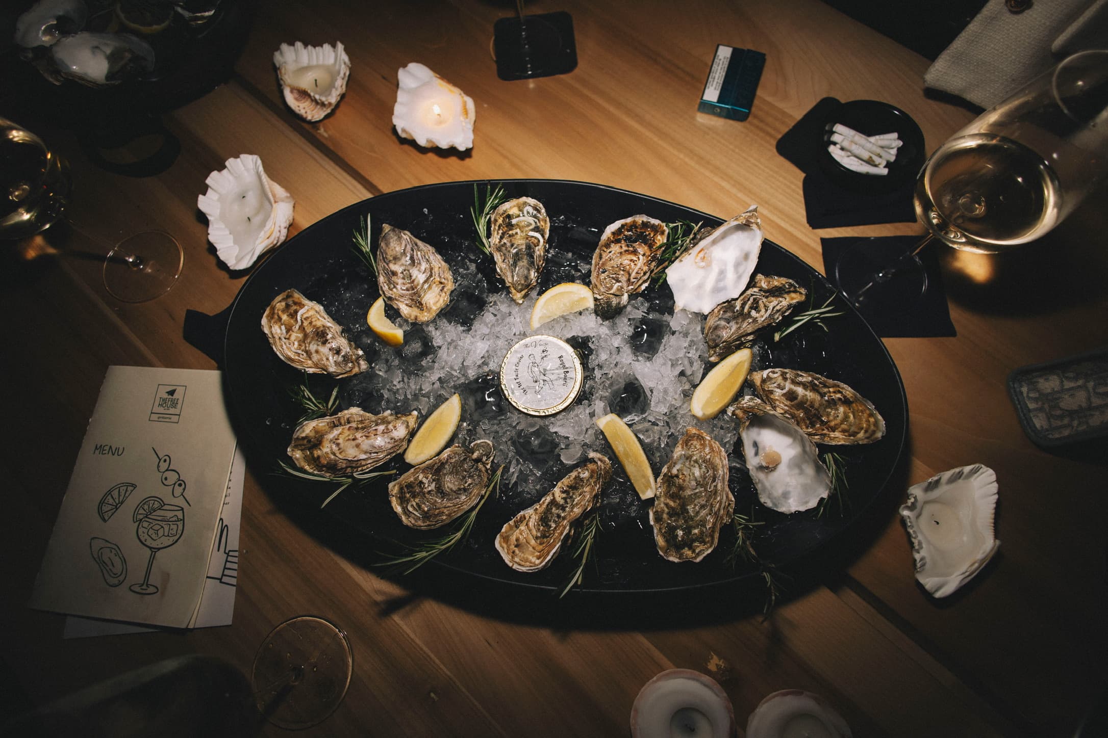 A platter of freshly shucked oysters on ice around a TheVtaste caviar tin
